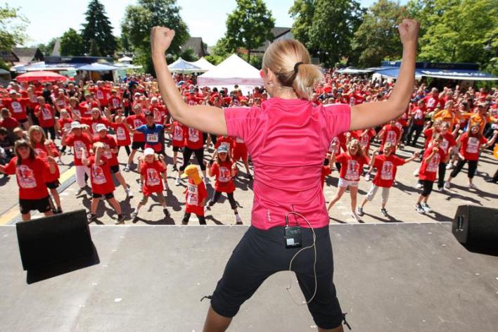 Fitness, Warm-up, Gruppenaktivität, Outdoor-Event, Trainerin, Menschenmenge, Sportveranstaltung
